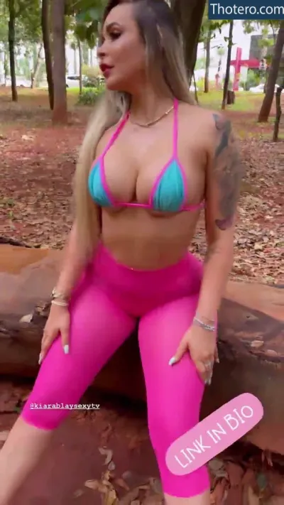 Kiara B - a woman in pink and blue bikini sitting on a log