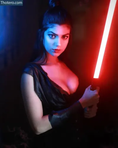 Kamila Ferreira - a woman in a black dress holding a red light saber