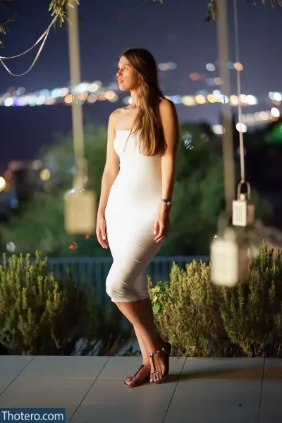 Yattana - woman in a white dress standing on a patio at night