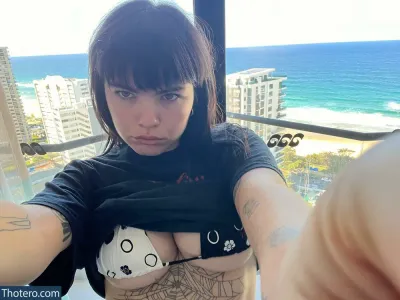 Benee - tattooed woman taking a selfie with her cell phone in front of a window