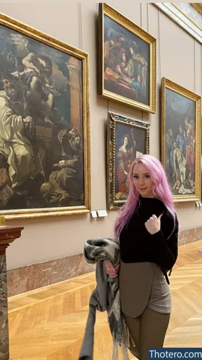 Jessu - woman with pink hair standing in front of paintings